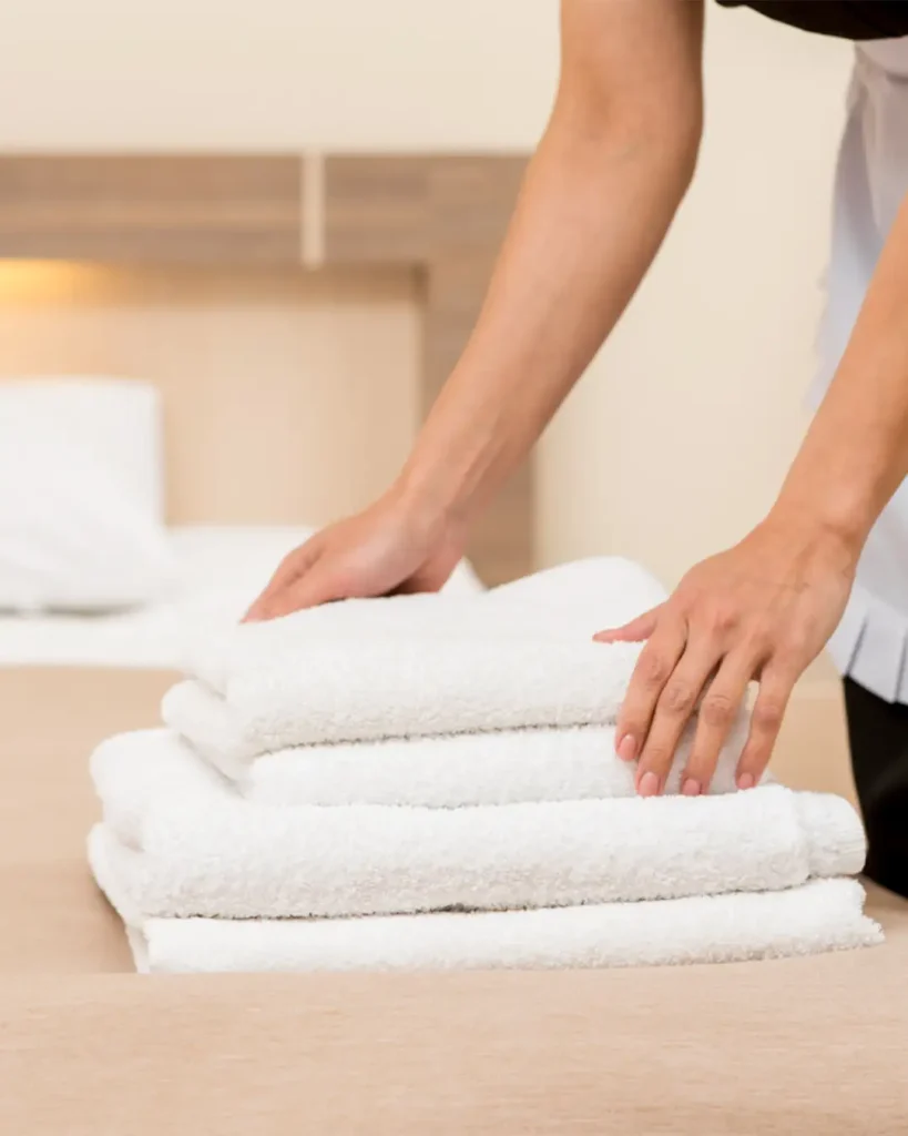 Chyžná ukladá čisté uteráky na posteľ